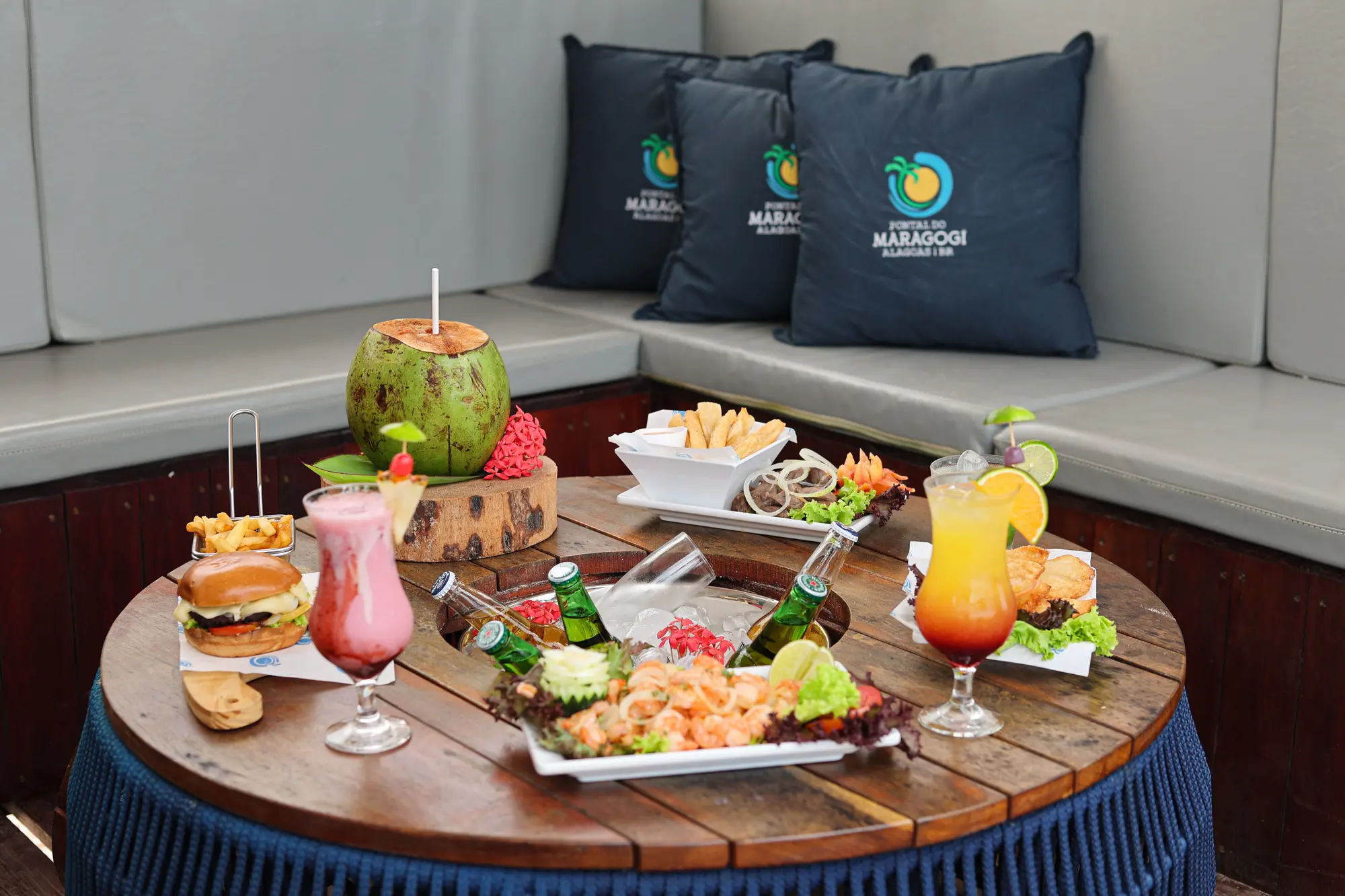 Mesa con picoteos, tragos y agua de coco frente al mar