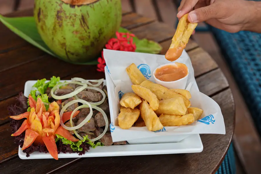 Porción de carne de sol con mandioca y agua de coco