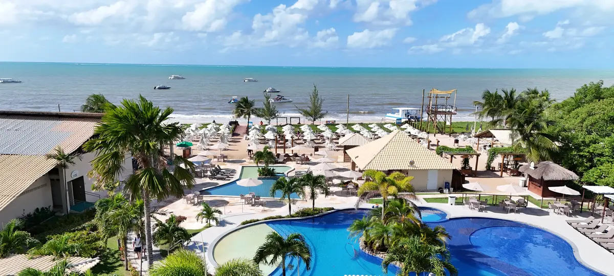 Vista aérea de Pontal do Maragogi: piscina entre palmeras, sombrillas en la arena y el mar